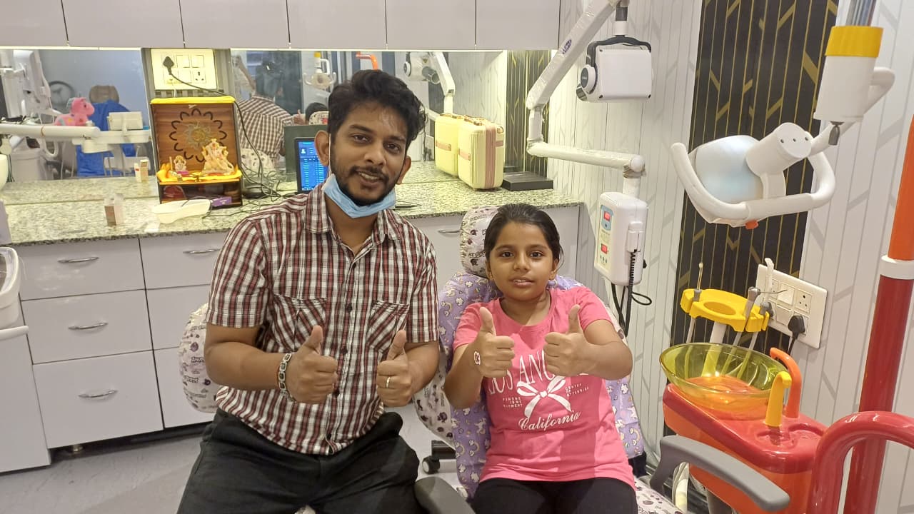 Dr. Rangan Ghosh and a young girl in the dental chair giving double thumbs up after her check-up at Tiny Tooth Dental, Lucknow