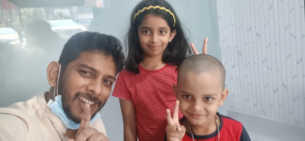Two young siblings making peace signs with Dr. Rangan Ghosh after their dental appointment at Tiny Tooth Dental