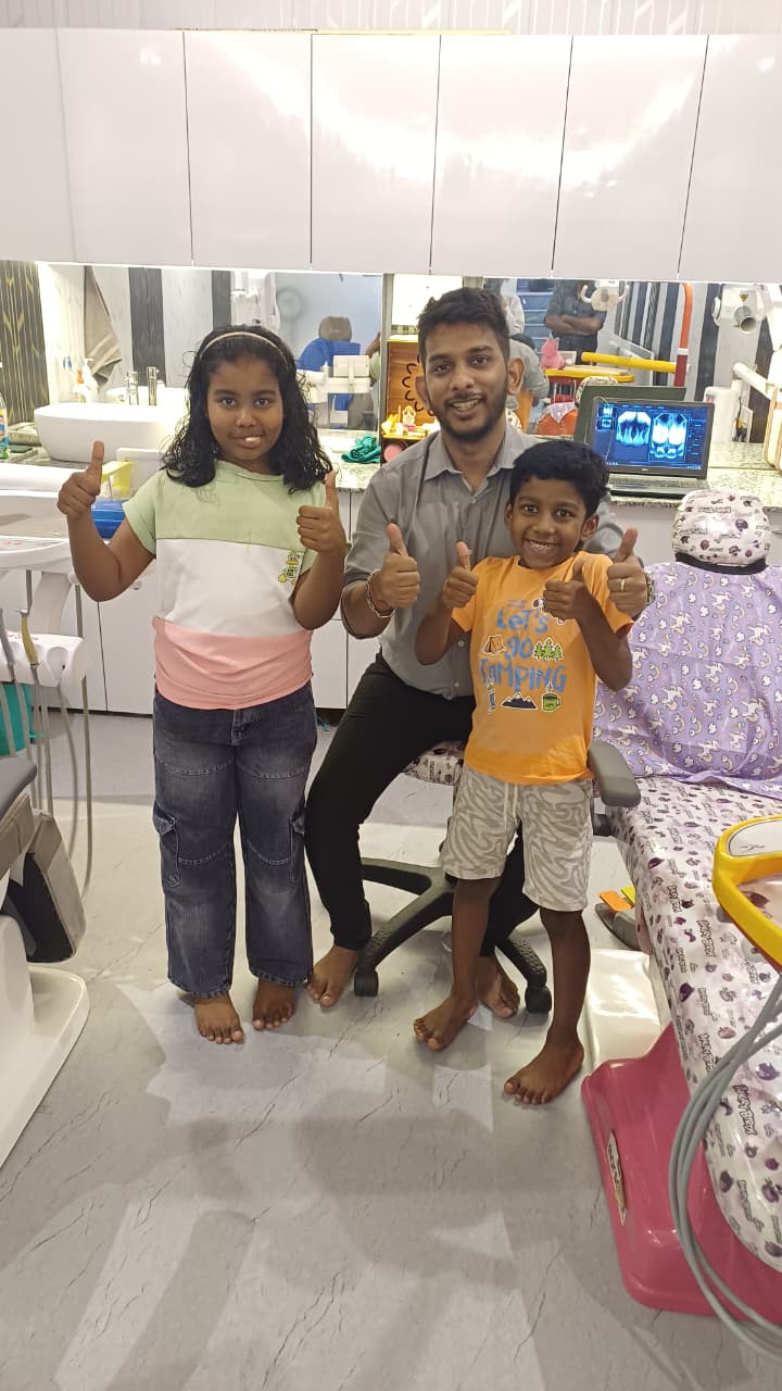 Dr. Rangan Ghosh with a brother and sister giving thumbs up beside their dental X-rays at Tiny Tooth Dental, Lucknow